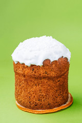 Easter cake, with dried fruits, raisins under white sugar icing with coconut, isolated on green background. Baking concept, traditional easter treats. Copy space