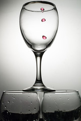 Drops of red wine falling into a transparent glass with splashes
