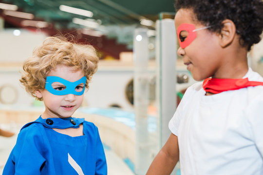 Two little boys wearing costumes of superheroes playing together in kindergarten
