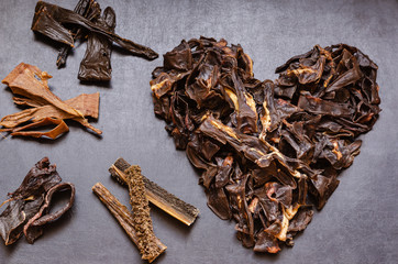 The image of the Heart is laid out from treats for dogs. Natural dried treats for dogs on a dark background. Treats for motivation at dog shows and training. Pet care. Pet supplies. Selective focus. 