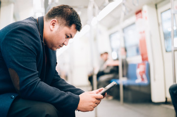Fototapeta premium Young business asian man using his digital tablet in Subway,train,metro