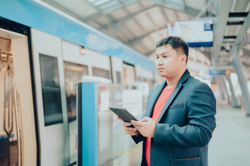 Young business asian man using his digital tablet in Subway,train,metro