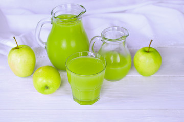 cocktail of apples with milk in glass jugs and glasses on the table close-up.