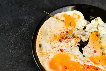 scrambled eggs with thyme and pepper and spices on a plate black