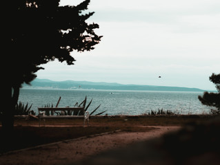 View of the adriatic sea, islands in the distance. Seen from sustipan hill in split,croatia. Lone bench in an old park stands on a cloudy day