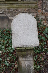 Verwitterter jüdischer Grabstein auf einem Steinständer