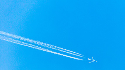 Four engined airplane during flight in high altitude with condensation trails