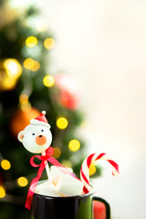 Christmas lollipops in a cup with Christmas decorations on a table on a light background. Gingerbread in the form of a minishka in a New Year's hat. Postcard