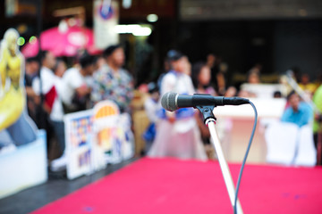 Selective focus on microphone on stage with blurred crowd of people in background