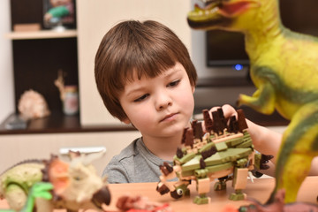 Child play with a dinosaur toys. Boy having fun playing with a toy dinosaur, little paleontologist