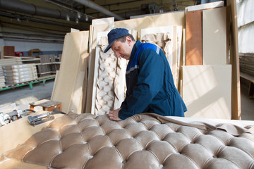  Wood processing plant.Worker in the workshop for the production of beds. The master makes luxury...
