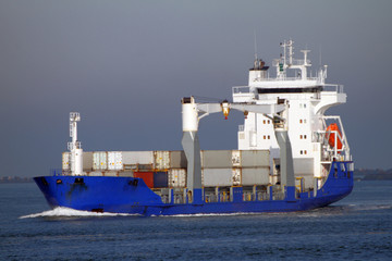 Blaues Feederschiff mit Containern erreicht den Hafen