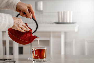 Woman hands with kettle and hot tea 