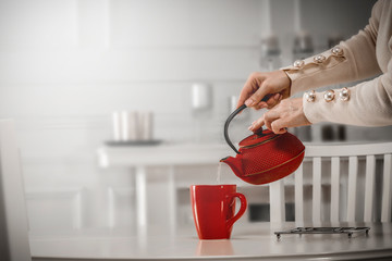 Woman hands with kettle and hot tea 