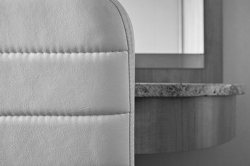 Detail or closeup of white leather backrest and parts of vanity desk with mirror in cabin or...