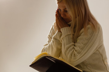 A young woman in prayer under dramatic light.