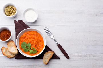 Pumpkin dish with toasted baguette slices, sour cream and spices on a brown cloth napkin.