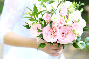A bride holding wedding bouquet from pink peonies. 