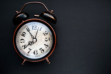 Old, vintage retro alarm clock on dark background.