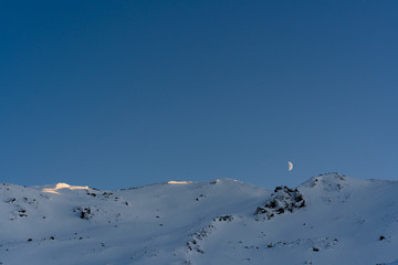 Mond über verschneiten Bergen