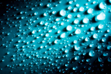 Blue drops of water macro on material in sunlight.