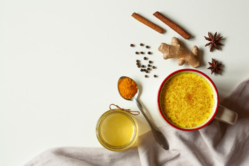 Golden milk with turmeric, honey, black pepper, cinnamon, star anise and ginger on a gray table. Traditional indian hot drink. Healthy, detox, diet beverage. Flat lay, top view, copy space.