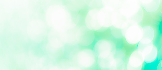 Fototapeta premium Abstract Bokeh Blue and green background of defocused glittering lights. Christmas, Party, New Year, luxurious background pattern concept. banner.