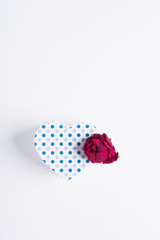 blue polka dot heart-shaped cardboard box next to pink with almost dry petals vertical
