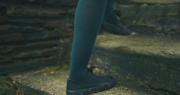 The feet of a young woman walking up some steps outdoors