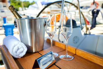 Romantic luxury evening on cruise yacht with champagne setting. Empty glasses and bottle with champagne and tropical sunset with sea background