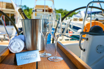 Obraz na płótnie Canvas Romantic luxury evening on cruise yacht with champagne setting. Empty glasses and bottle with champagne and tropical sunset with sea background