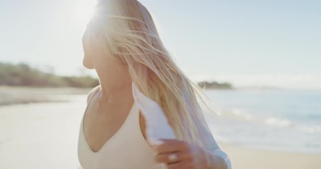 Young attractive woman smiling and walking on the beach at sunrise on her tropical vacation, happy blonde woman enjoying the beach - Powered by Adobe