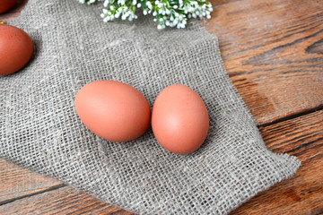 Close up natural color eggs with sackcloth on rustic wooden background. Easter minimalist or health eating composition.