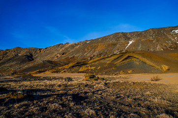 Fumarole fields of Iceland covered with yellow brimstone with boiling mud craters against the winter sky