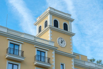 Fototapeta na wymiar Tivat, Montenegro, December 16, 2019: Facade of the building of the Regent hotel on the Tivat embankment. The walls of the building are light yellow in the background of a blue sky