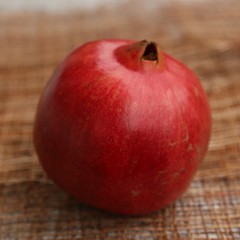 Fototapeta na wymiar Round red fruit pomegranate on the sack on the table