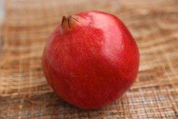 Fototapeta na wymiar Round red fruit pomegranate on the sack on the table