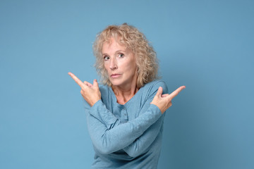 Mature blonde woman pointing to both sides with fingers, different direction having disagree...