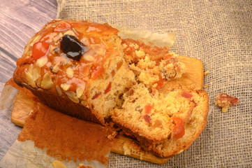 A sliced home-made Christmas cake on a wooden Board on a table covered with a homespun cloth.
