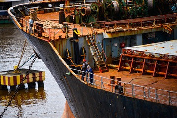 Two seafarers working on the main deck of old rusty bulk carrier. Vessel in very bad condition.