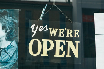 A sign on the glass door of a store or cafe with the inscription Yes we are open
