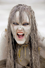 A young woman's face is covered with mud and dirt. Her hair is tangled in a mess. Her facial...
