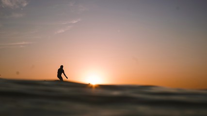 silhouette of woman surfing at sunset