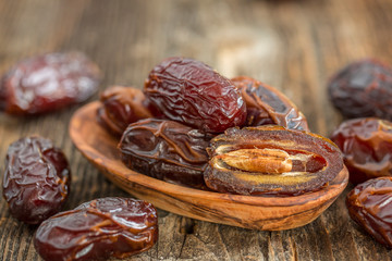 Juicy dates in a bowl on a old wooden table .