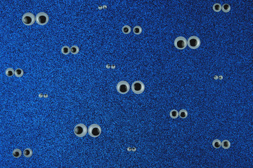 Many Pair of Googly Eyes on blue glitter Background.