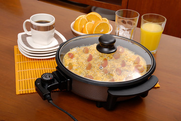 Electric multifunctional pan; photo on wooden background