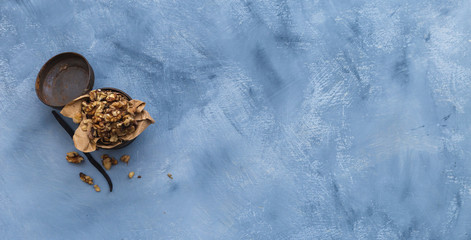 Walnuts in a rusty can on a grunge grey tabletop. Flat lay scenery with dried walnuts. Healthy vegan snack with vanilla stick. Copy space.