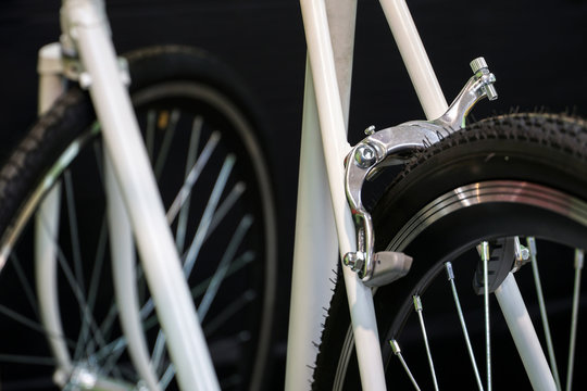 Road bike in the workshop. Bicycle repair. White bicycle on a black background. Installation of new equipment. Tire and rear brake closeup. Preparations for the competitions.