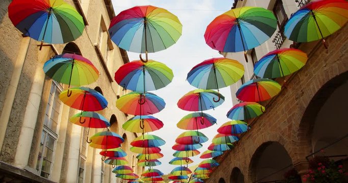 Colorful umbrellas open in the sky over a town street as a decoration, 4k