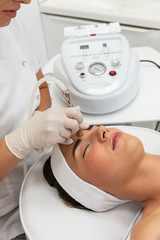 Kosmetolog wykonuje zabieg mikrodermabrazji skóry twarzy kobiety w salonie kosmetycznym. Kosmetologia i profesjonalna pielęgnacja skóry. Medycyna estetyczna